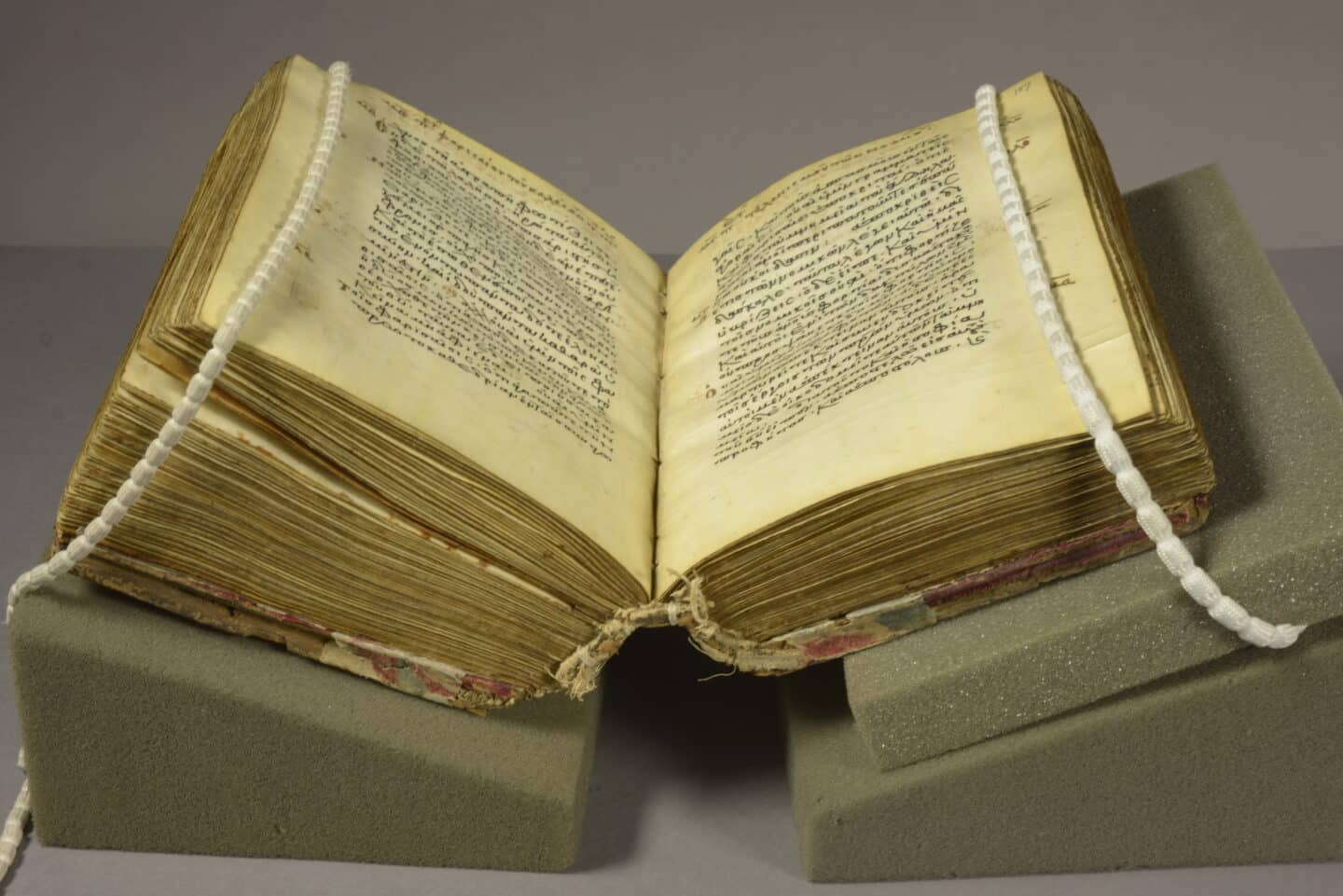 A thick manuscript lying open on raised acrylic supports.